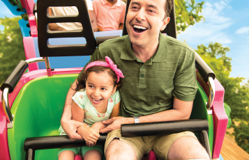 Man and a child on a children's roller coaster